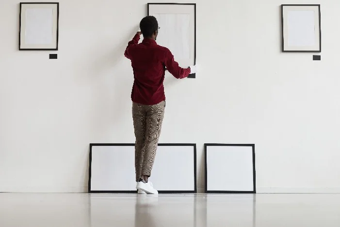 Person bringt Bild an